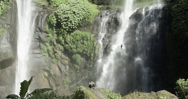 Man sitting near a waterfall