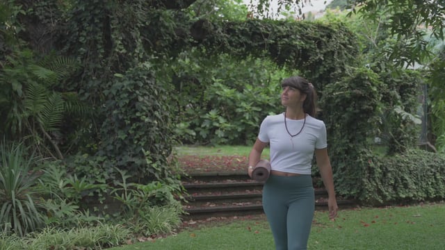 Yoga teacher walking in the park while holding a yoga mat