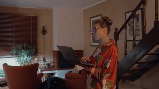 Una niña con una computadora portátil se encuentra en la casa.