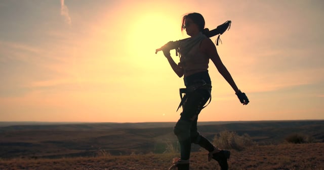  A woman with a weapon goes through a wasteland