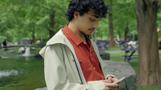 Un chico usa un teléfono inteligente en un parque.