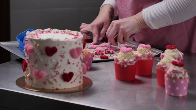 Mujer decora cupcakes con corazones rosas