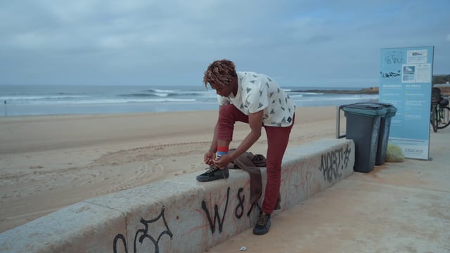 A young man tying his shoelaces at the beach