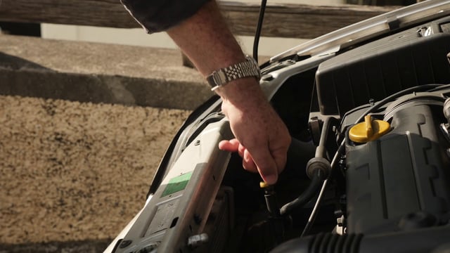 Man checks the oil level of a car