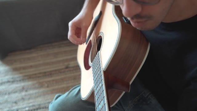 A guy playing the guitar carefully
