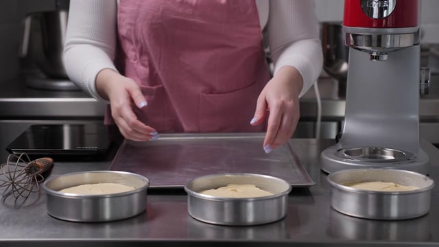 Pastelero coloca moldes para pasteles en una bandeja para hornear