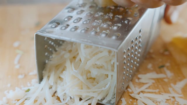 Tiras de queso rallado caen en el rallador de queso