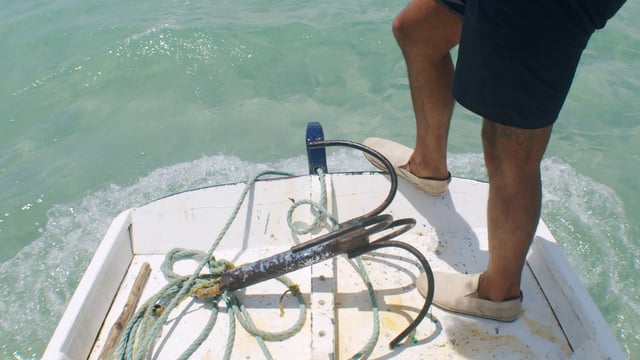 Pies de pie en el borde delantero de un barco de pescadores local