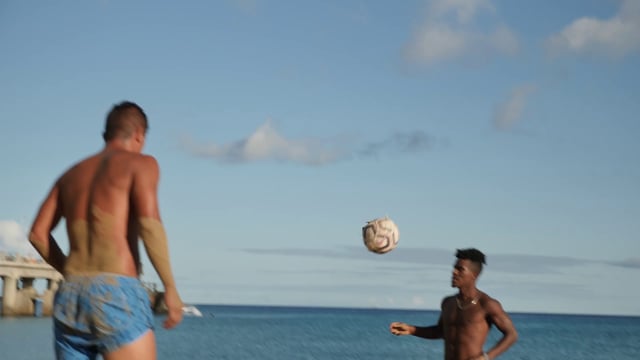 Guys playing football on the beach