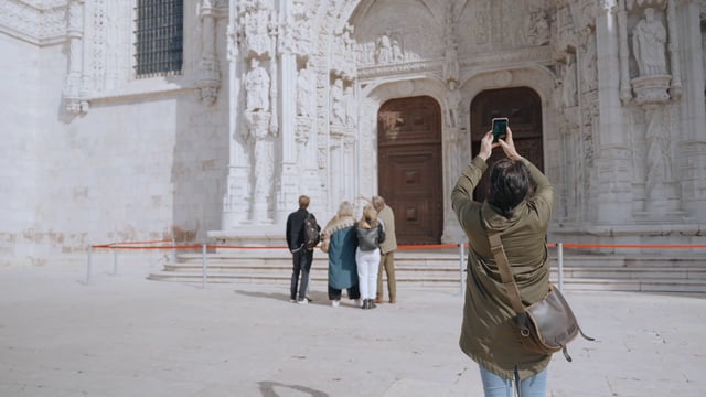 A woman taking a photo of Jeronimos Monastery