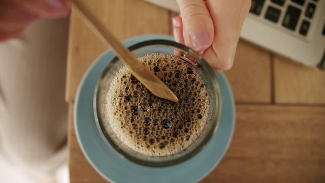 Stirring coffee with a wooden spoon