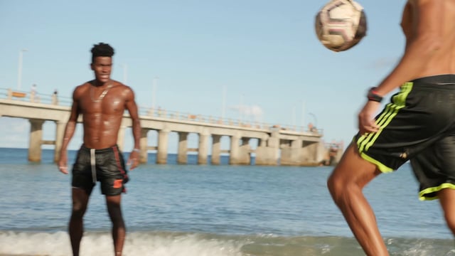 Guys kicking a ball to each other on the beach