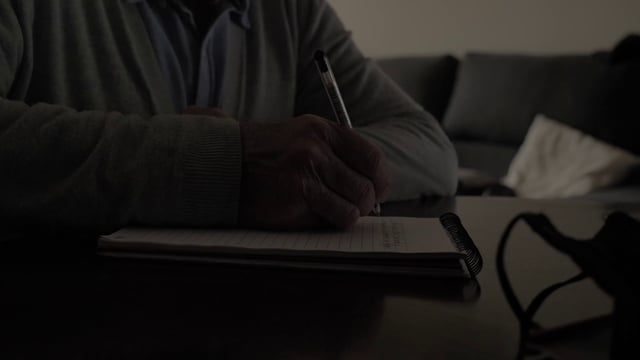 Cerca de la mano de un anciano escribe algo en un cuaderno