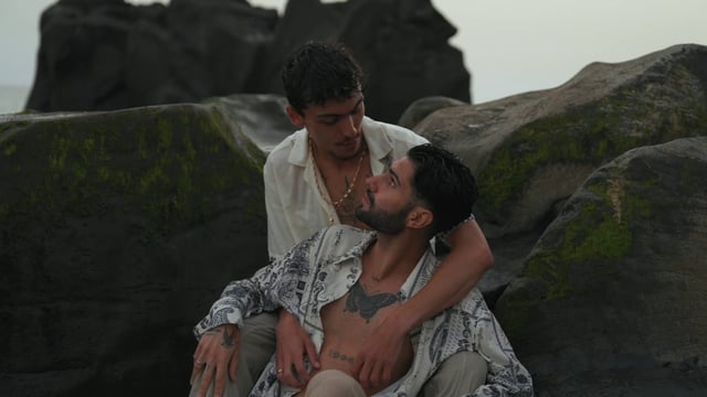 Una pareja gay amorosa se sienta en una roca