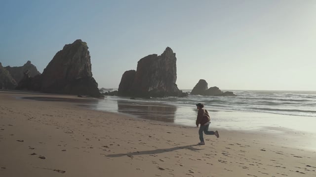 A guy running along the rocky coast on Ursa beach in Portugal