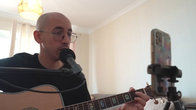 A guy singing a song and playing a guitar in a home studio