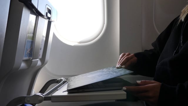 Woman opening laptop on plane