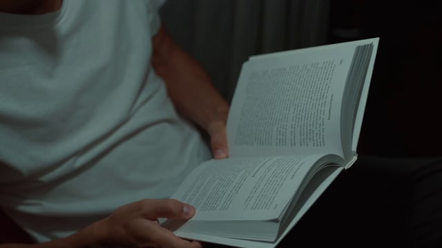 Un hombre está leyendo un libro tarde en casa.