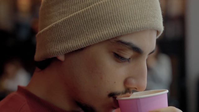Un chico bebe café en el primer plano de la cafetería