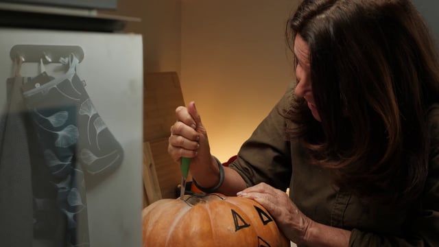 Happy woman carving a pumpkin