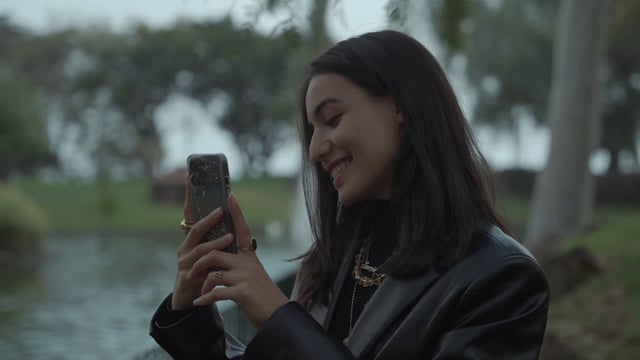 A girl smiles while taking photos on her smartphone