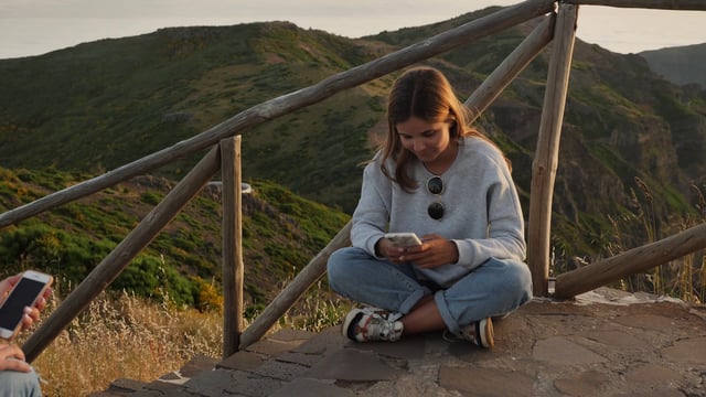 Mujeres enviando mensajes de texto en la cima de una montaña