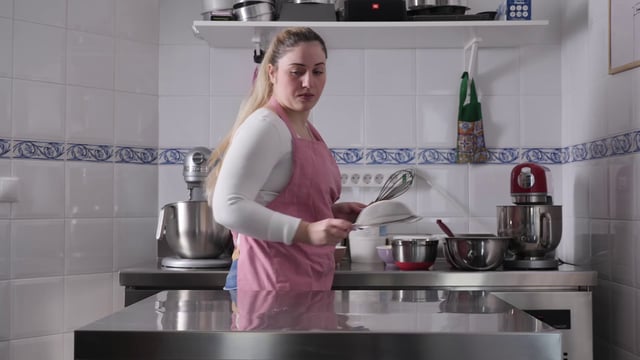 Una mujer extiende utensilios de cocina sobre la mesa