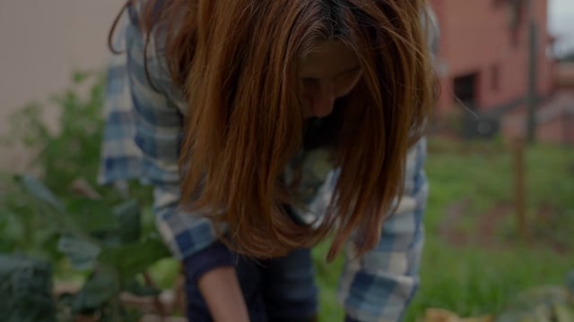 Una mujer corta verduras en un jardín.