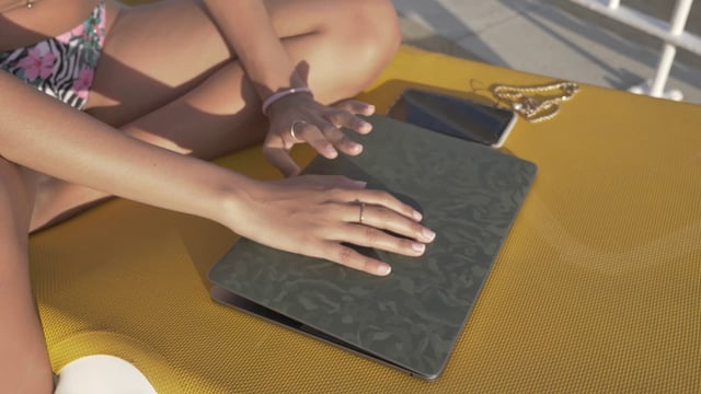 Manos femeninas abren un portátil en una tumbona