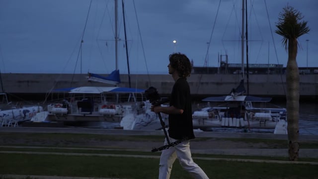 Filmmaker walking past yachts