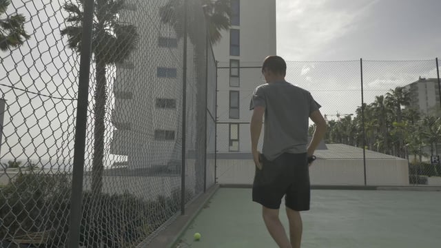 Man placing a tennis ball in his pocket