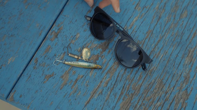 A fisherman putting sunglasses on