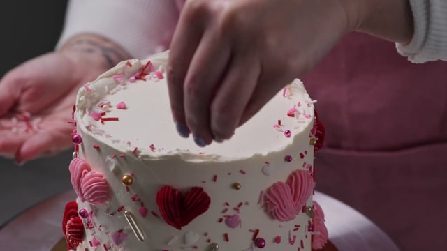 Un pastelero decora un pastel con chispas