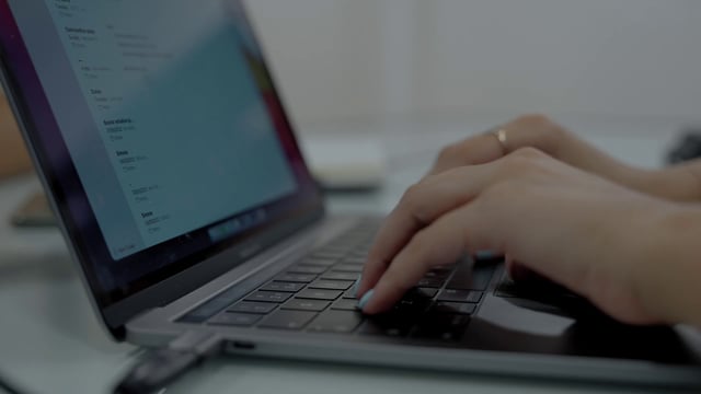 Woman with blue nails typing on a laptop