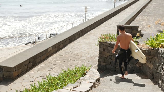 Man carrying a surfboard down the steps