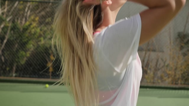 Una jugadora de tenis hace una cola de caballo en una cancha de tenis