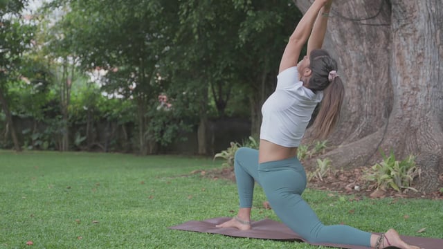 Chica hace pose de guerrero de yoga en un césped