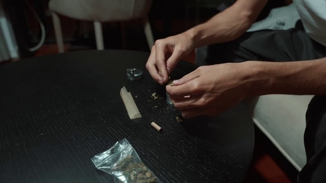 一名男子在草药研磨机中装满大麻