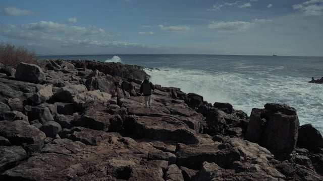 一个家伙在岩石海岸寻找钓鱼的地方