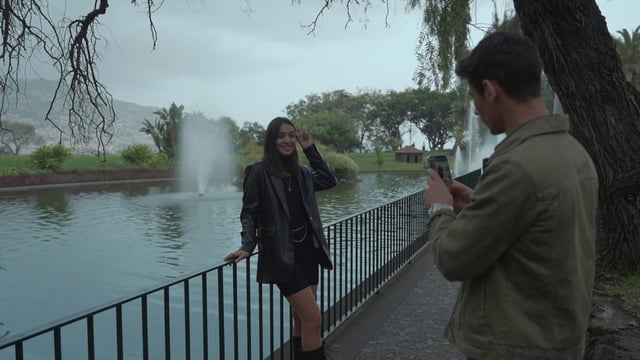 Un chico fotografía a su novia en un parque.