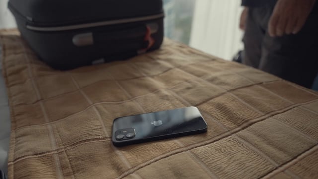 A man grabbing his smartphone from a bed