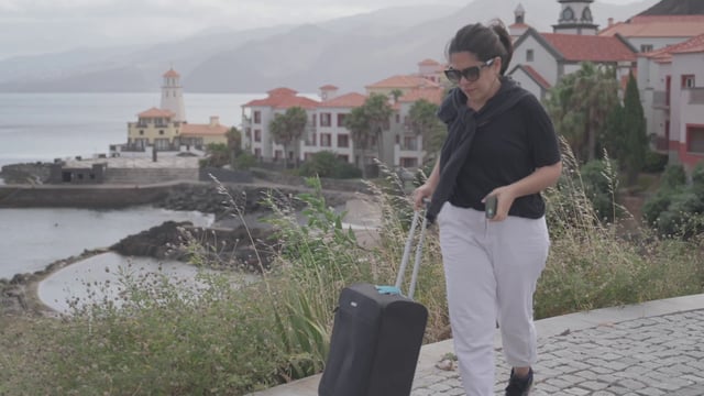 Brunette woman walking with a travel suitcase